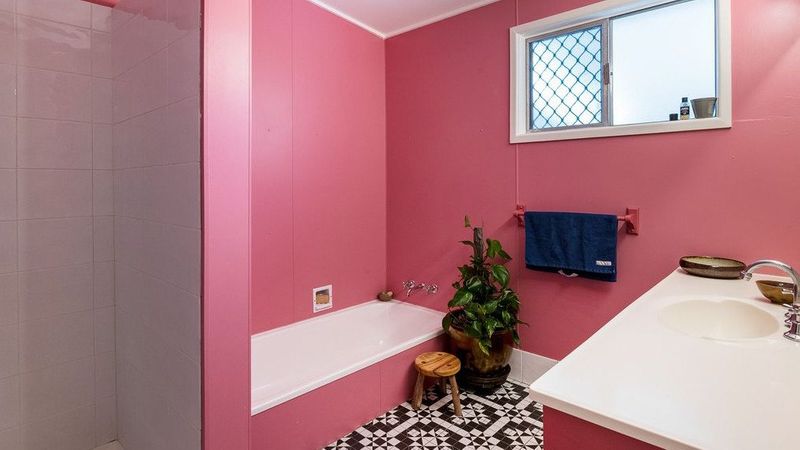 艺术家的偏心Sunnybank房子有书架的墙壁和粉红色的浴室